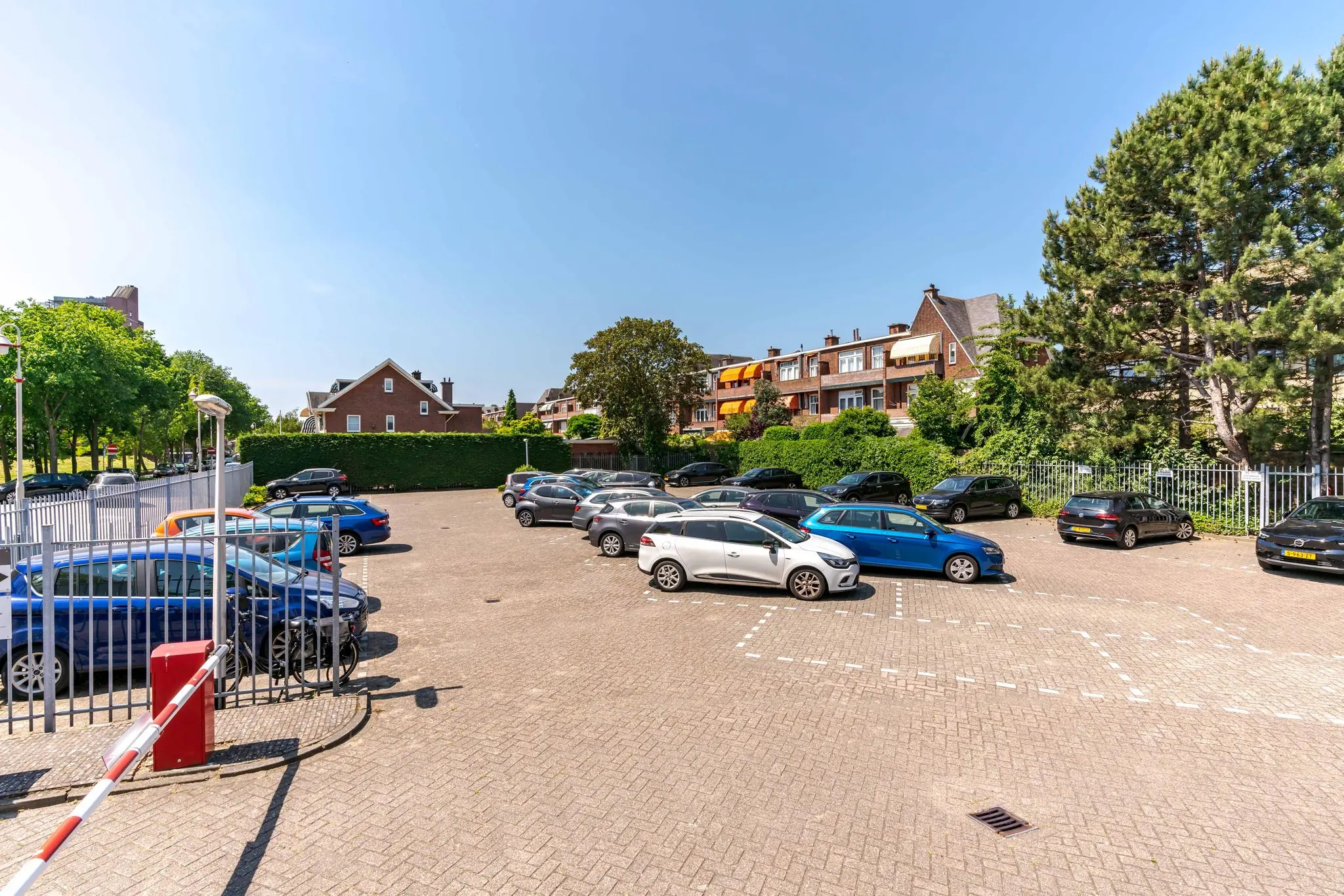 Parkeerplaats aan de Van Alkemadelaan met diverse geparkeerde auto's en omliggende woningen op een zonnige dag.